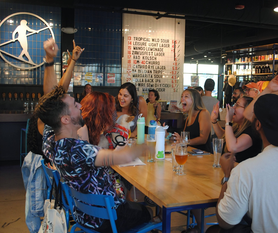 The Psychology of Trivia Nights: Building Community and Loyalty at Your Bar 1 Group of friends cheering and celebrating a trivia win at a bar with drinks and laughter