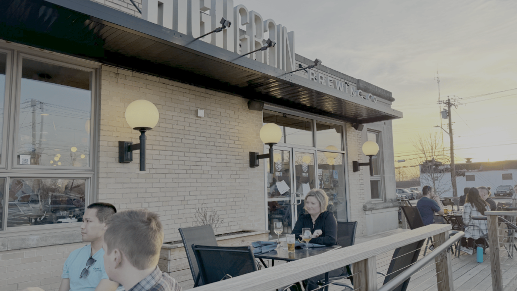 Guests enjoying drinks on the outdoor patio at HighGrain Brewing Co. during sunset, creating a relaxed neighborhood brewery vibe.