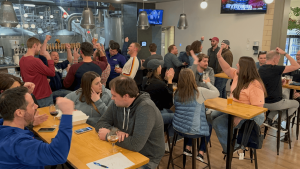 Crowded brewery filled with excited trivia players cheering and celebrating during a weekly trivia night event.